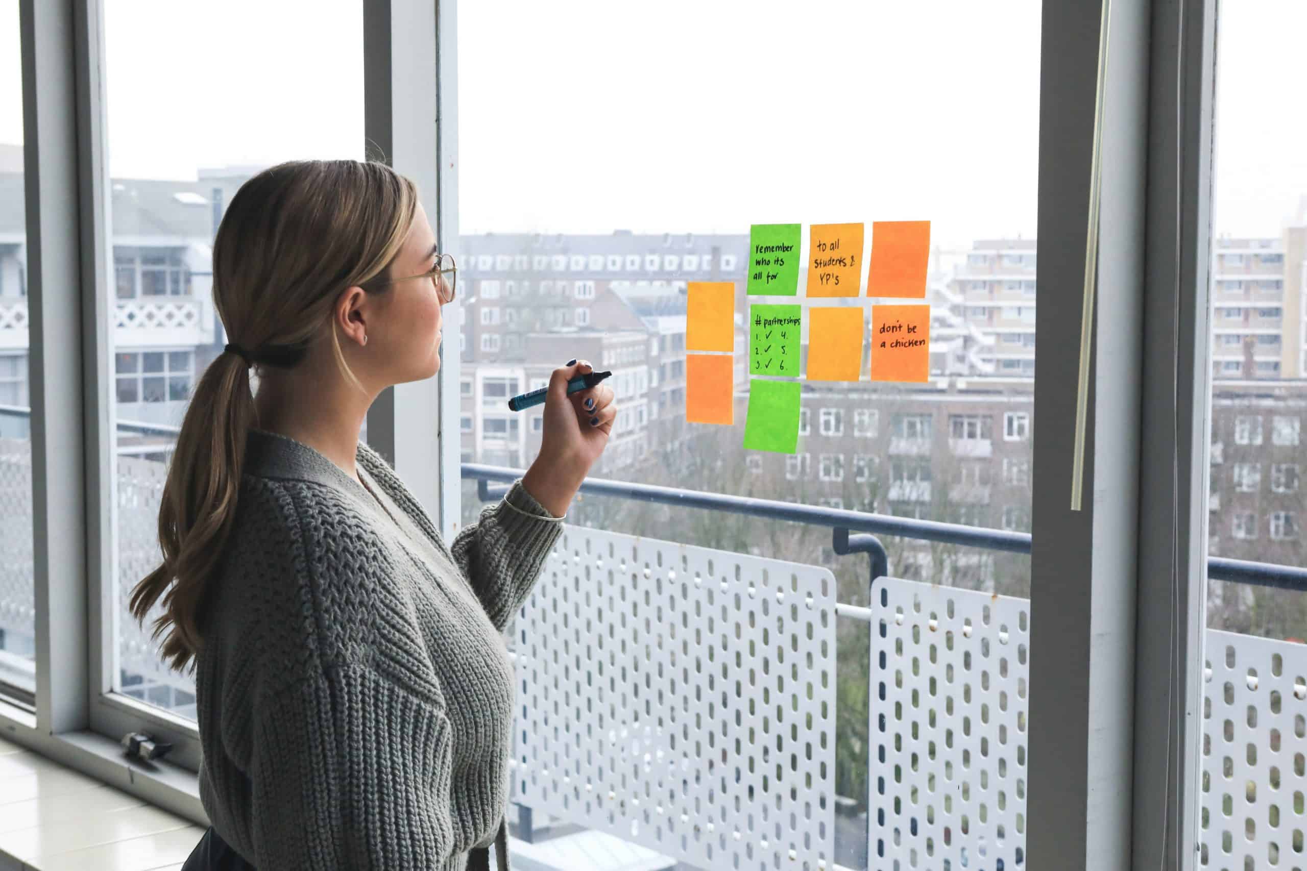 Colorful sticky notes on glass wall during brainstorming session, modern office, fashion industry planning.