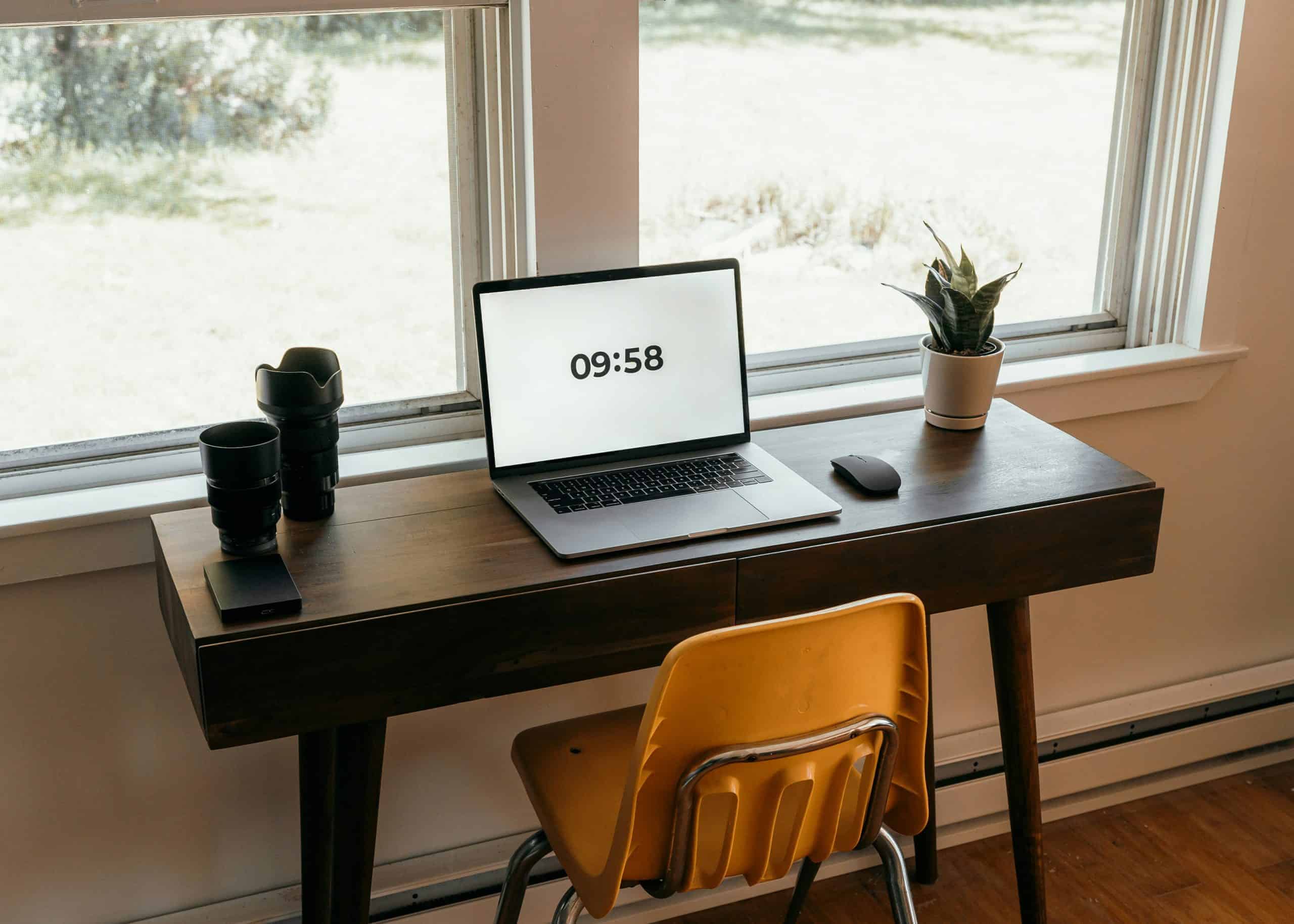 Desk with a laptop showing 09:58, showing work space for digital fashion and creative industry professionals.