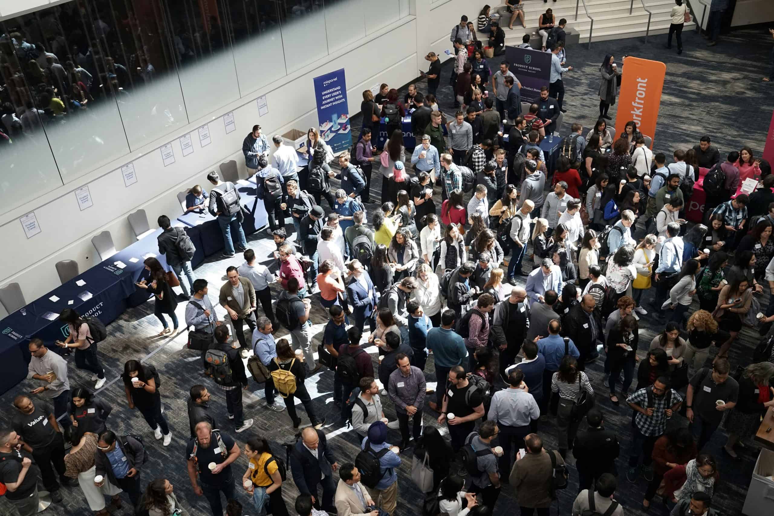 Busy fashion conference registration area with attendees and exhibitor booths.