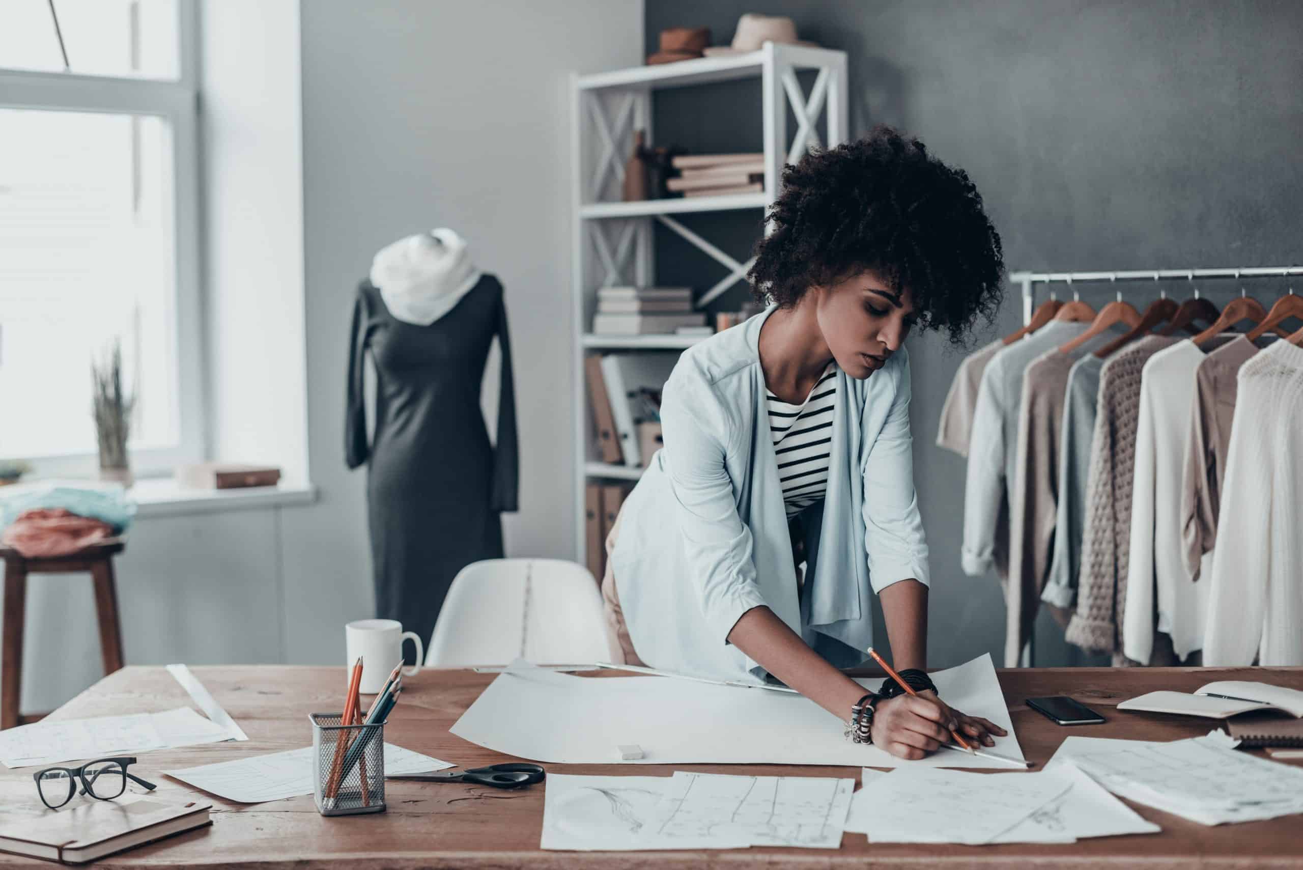 1. Fashion designer working on clothing sketches in a modern studio.
