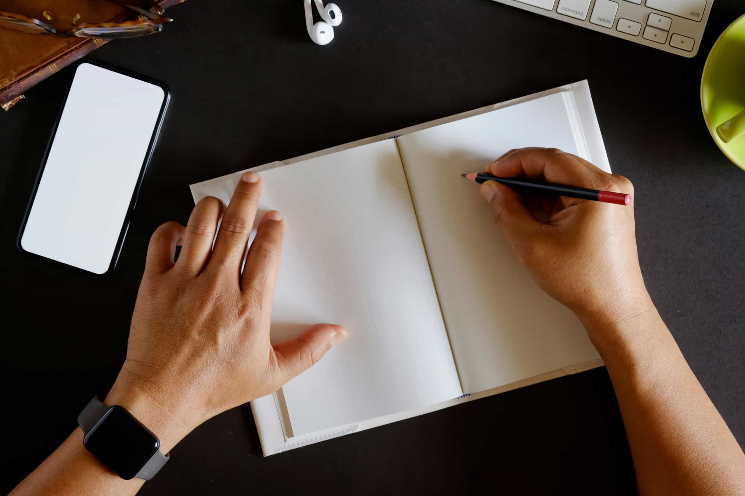 1. Open blank notebook on a dark desk with writing tools for fashion industry notes.
