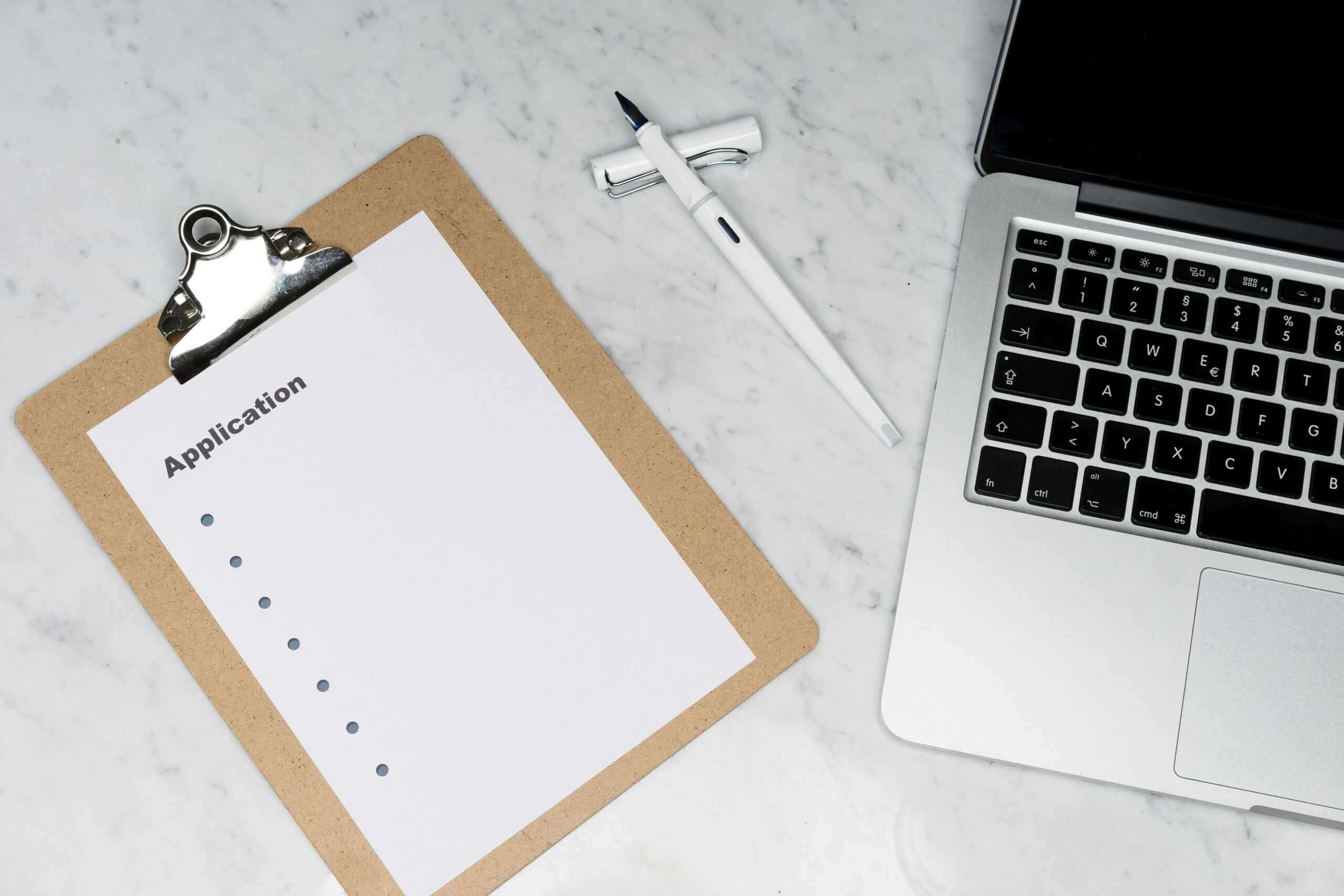 Blank application form on clipboard next to laptop, illustrating why top fashion candidates don't apply through traditional job posting