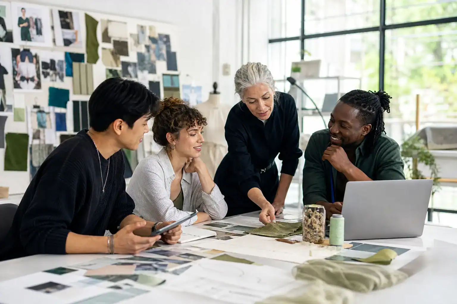 Early-career fashion professionals collaborating with a senior mentor.