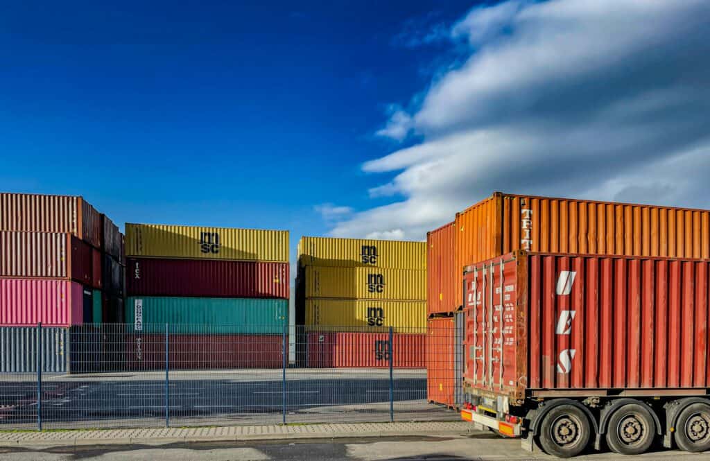 Stacks of multicolored shipping containers at a freight yard, symbolizing the global logistics and supply-chain stages that fashion staffing agencies support.
