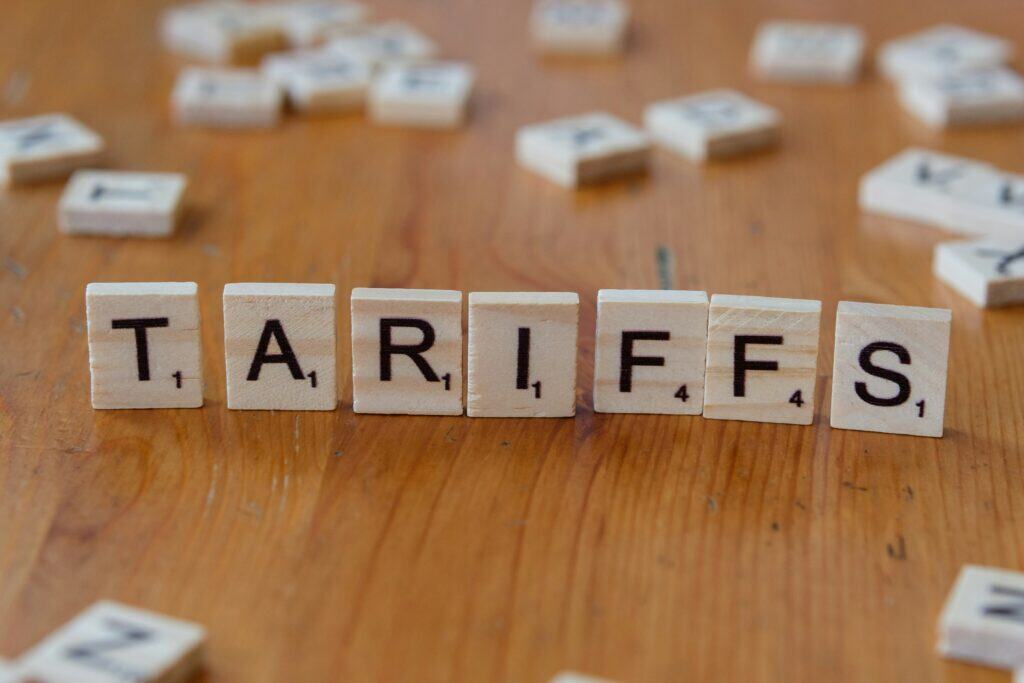 Letter tiles spelling out tariffs on a neutral background symbolizing global trade changes affecting fashion supply chains