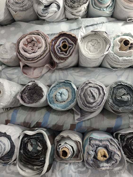 Fashion Recruiter vs. Generalist Staffing Agency: What’s the Difference? 1 Rolls of colorful textiles stacked in a sourcing warehouse representing the diverse supply chain roles a fashion staffing agency fills